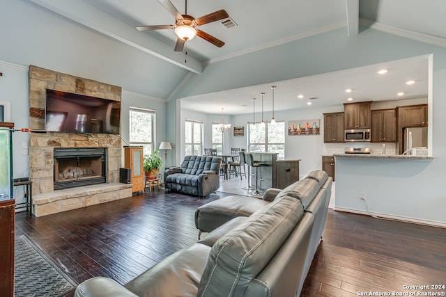 living room with vaulted ceiling with beams, a stone fireplace, ceiling fan with notable chandelier, crown molding, and dark hardwood / wood-style flooring