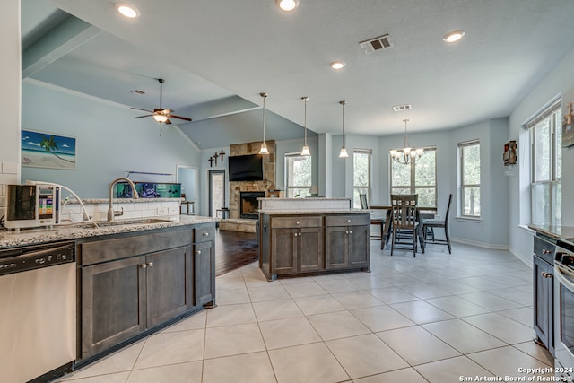 kitchen featuring pendant lighting, dark brown cabinets, a stone fireplace, appliances with stainless steel finishes, and ceiling fan with notable chandelier