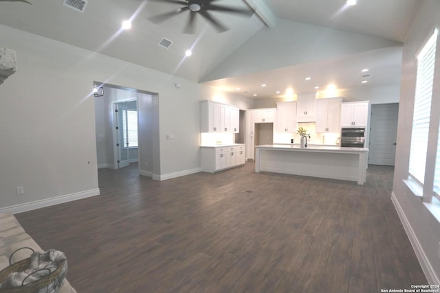 unfurnished living room featuring ceiling fan, beamed ceiling, sink, dark wood-type flooring, and high vaulted ceiling