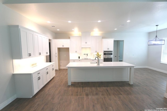 kitchen featuring dark hardwood / wood-style floors, a kitchen island with sink, sink, white cabinetry, and double oven