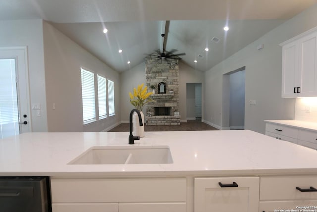 kitchen featuring ceiling fan, lofted ceiling, sink, stainless steel dishwasher, and a fireplace