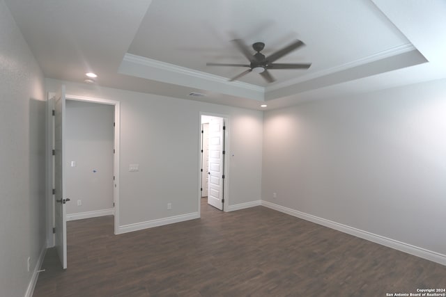 unfurnished bedroom featuring ornamental molding, ceiling fan, a raised ceiling, and dark wood-type flooring