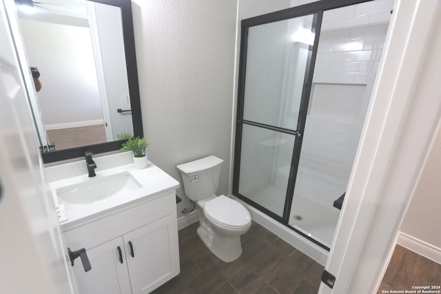 bathroom with hardwood / wood-style flooring, vanity, toilet, and a shower with shower door