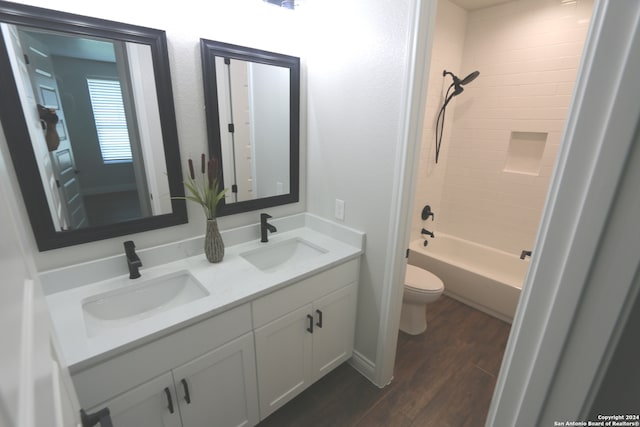 full bathroom with hardwood / wood-style floors, tiled shower / bath, vanity, and toilet