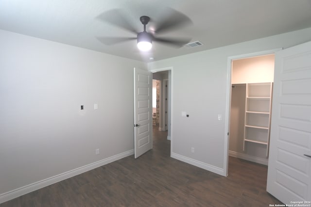 unfurnished bedroom with ceiling fan, a closet, dark hardwood / wood-style floors, and a walk in closet