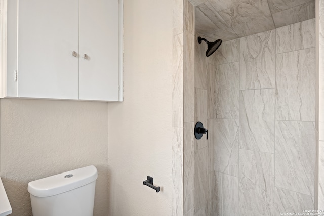 bathroom featuring tiled shower and toilet