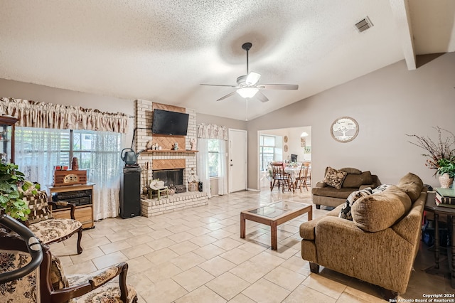 living room featuring ceiling fan, light tile patterned floors, a textured ceiling, lofted ceiling with beams, and a fireplace