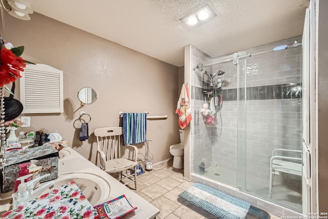 bathroom featuring a shower with shower door, a textured ceiling, toilet, sink, and tile patterned floors