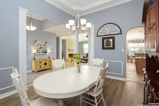 dining space featuring light hardwood / wood-style floors, ornamental molding, a large fireplace, and ceiling fan