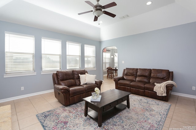 tiled living room with ceiling fan and a tray ceiling