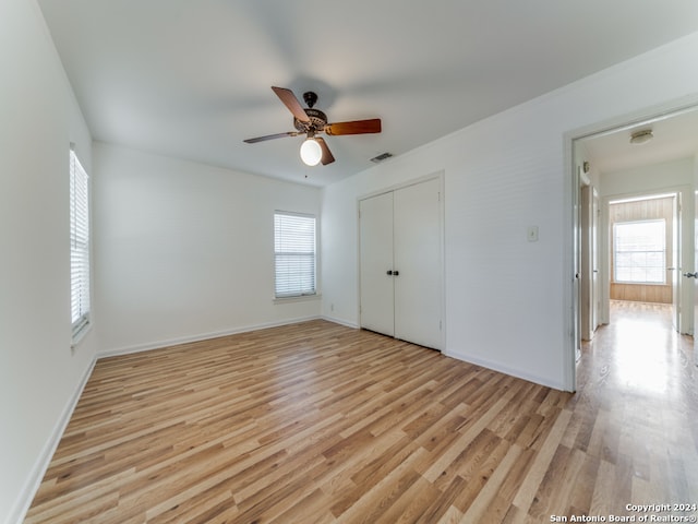 unfurnished bedroom featuring a closet, light hardwood / wood-style floors, and ceiling fan