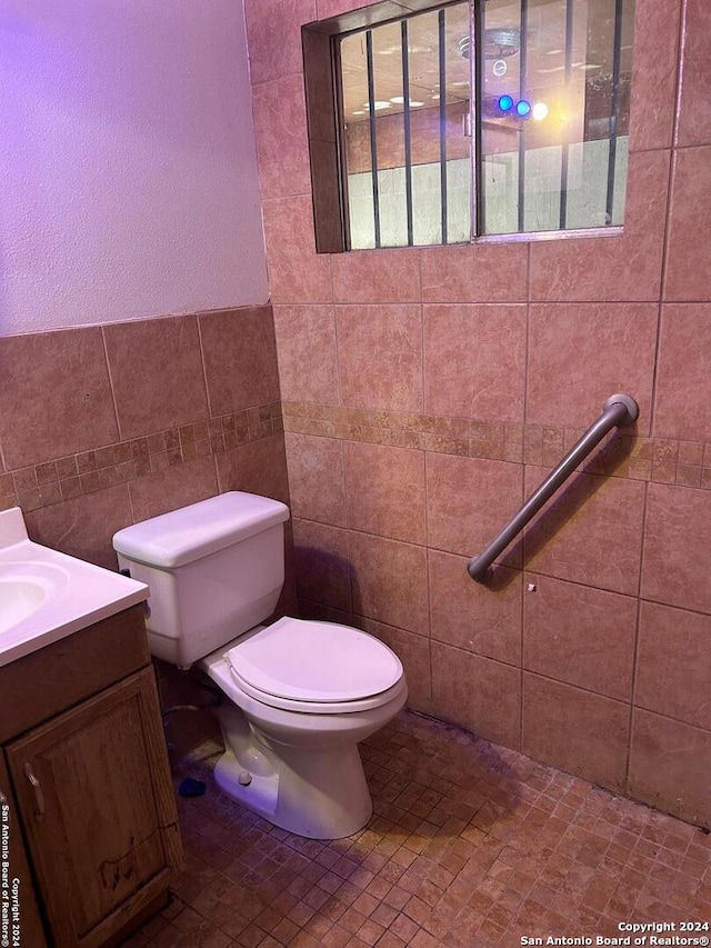 bathroom with tile walls, vanity, and toilet