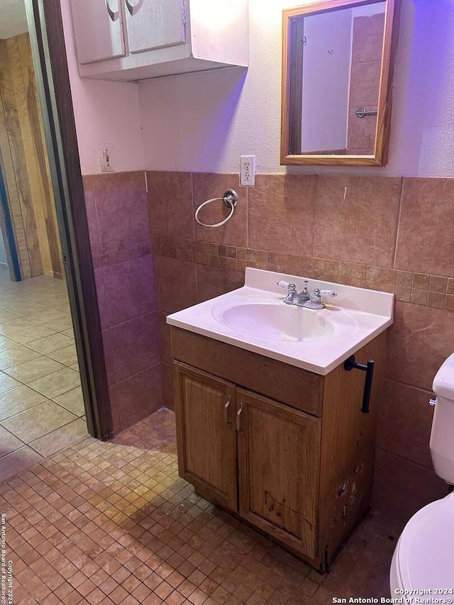 bathroom with tile walls, vanity, and toilet