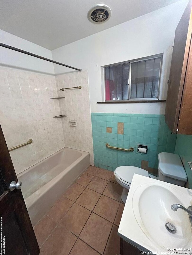 full bathroom featuring tile walls, tile patterned flooring, tiled shower / bath combo, vanity, and toilet