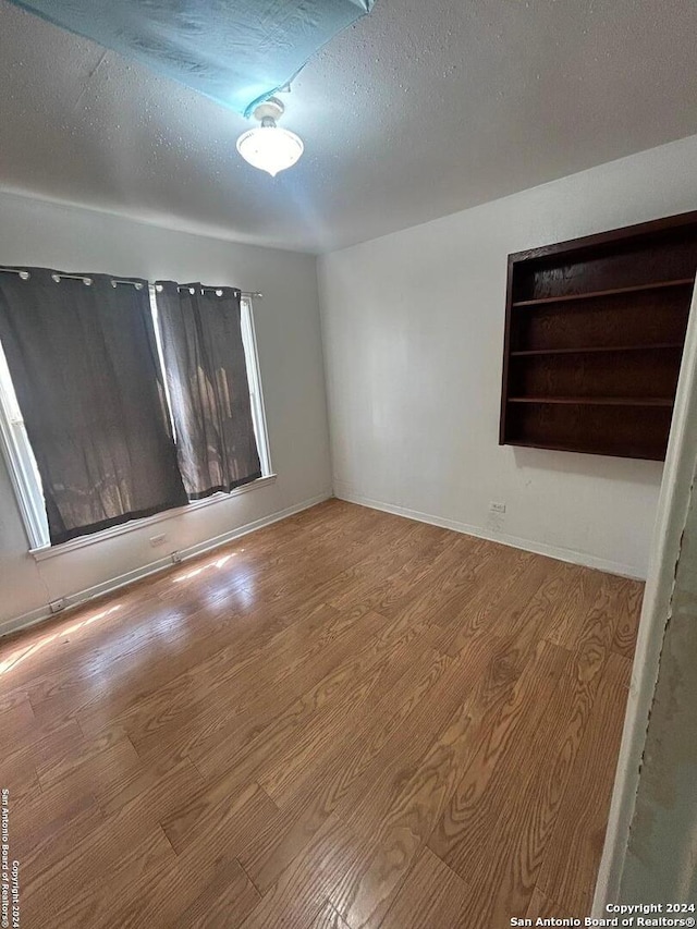 unfurnished room with wood-type flooring and a textured ceiling