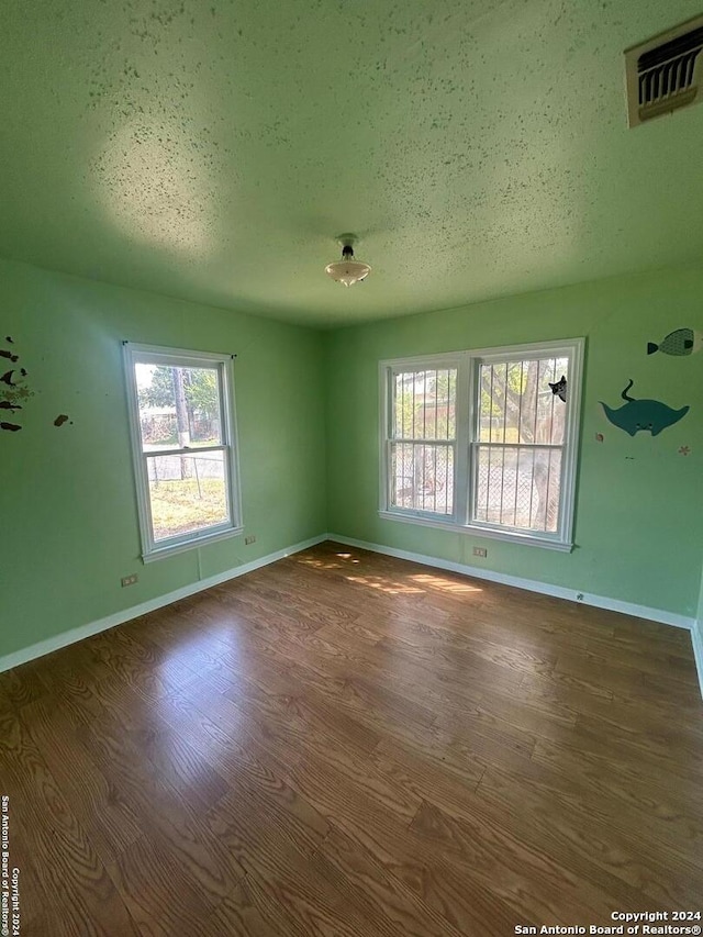 unfurnished room with a textured ceiling and dark wood-type flooring