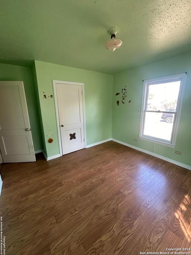 spare room featuring a textured ceiling and dark hardwood / wood-style floors