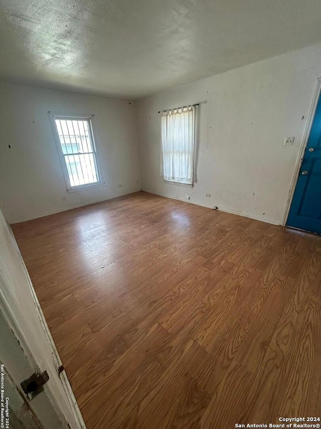 spare room featuring light wood-type flooring and a textured ceiling