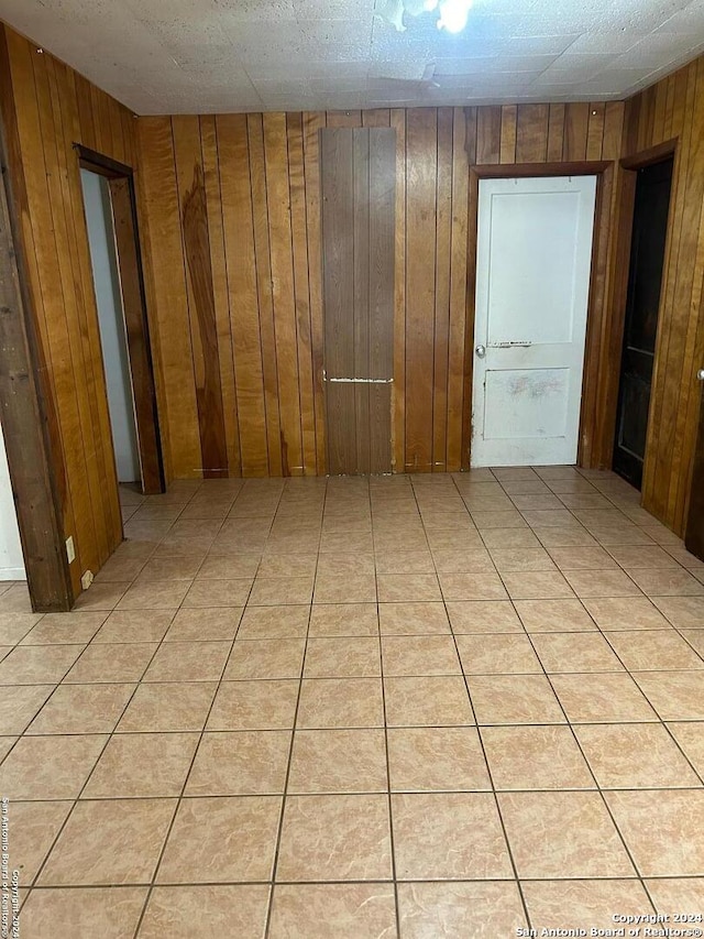 empty room featuring light tile patterned flooring and wooden walls