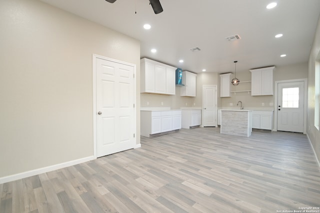 unfurnished living room featuring light hardwood / wood-style floors, sink, and ceiling fan