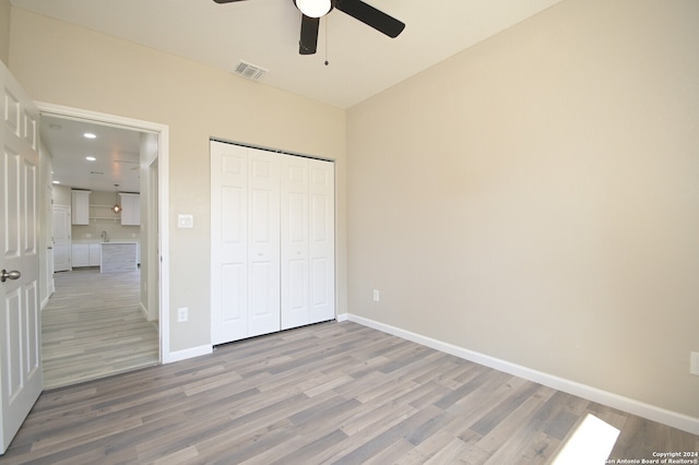 unfurnished bedroom with wood-type flooring, ceiling fan, and a closet