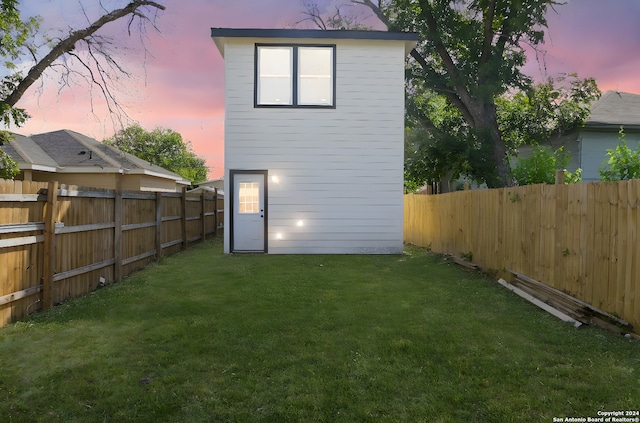 back house at dusk featuring a yard