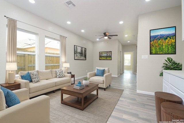 living room featuring ceiling fan, light wood-type flooring, and a healthy amount of sunlight