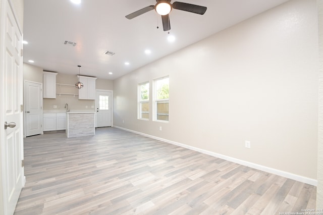 unfurnished living room featuring light hardwood / wood-style floors, sink, and ceiling fan