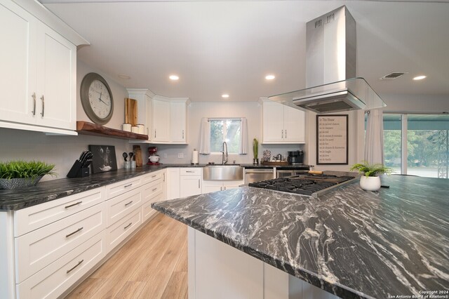 kitchen with light hardwood / wood-style floors, island range hood, white cabinetry, and sink