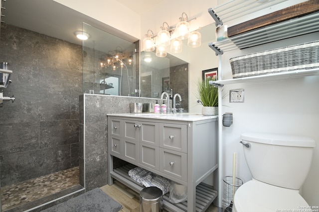 bathroom with tiled shower, vanity, and toilet