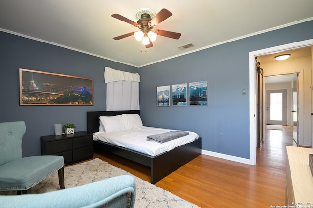 bedroom with wood-type flooring, ornamental molding, and ceiling fan