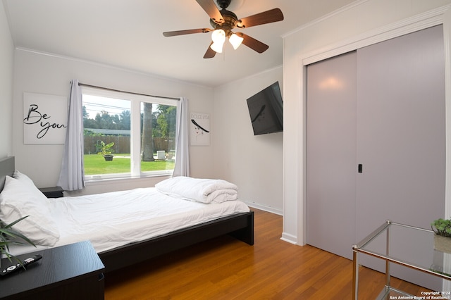 bedroom featuring ceiling fan, hardwood / wood-style flooring, a closet, and ornamental molding