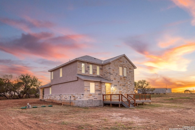 back house at dusk featuring a wooden deck