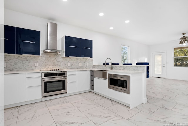 kitchen with wall chimney exhaust hood, white cabinets, stainless steel appliances, and plenty of natural light