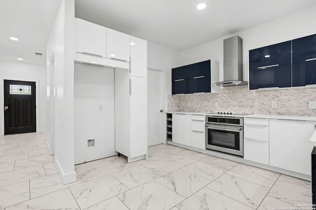 kitchen with white cabinets, wall chimney exhaust hood, oven, and tasteful backsplash