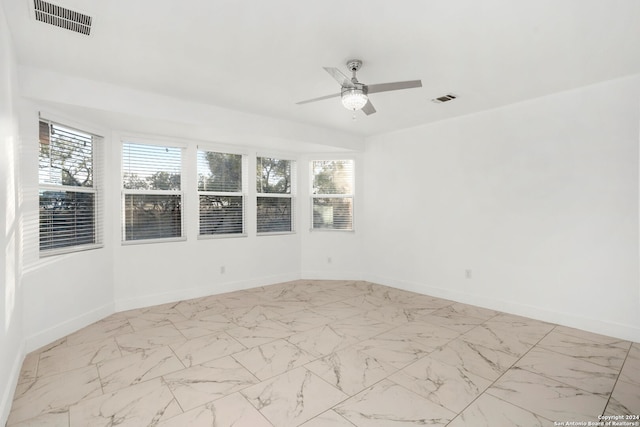 empty room featuring ceiling fan and a wealth of natural light