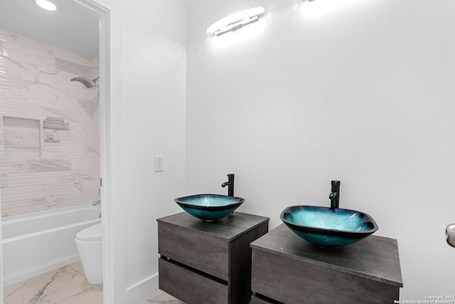 full bathroom with tiled shower / bath, vanity, and toilet