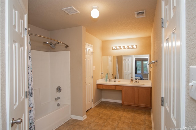 bathroom featuring a textured ceiling, vanity, and shower / tub combo with curtain