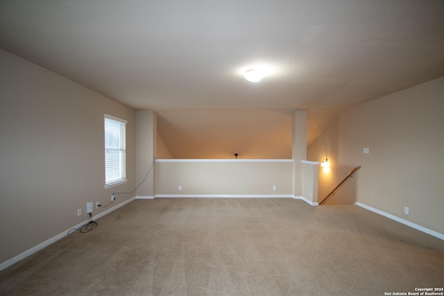 spare room with lofted ceiling, carpet floors, and a textured ceiling