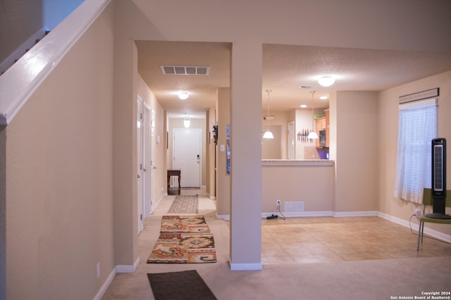 hall with light carpet and a textured ceiling