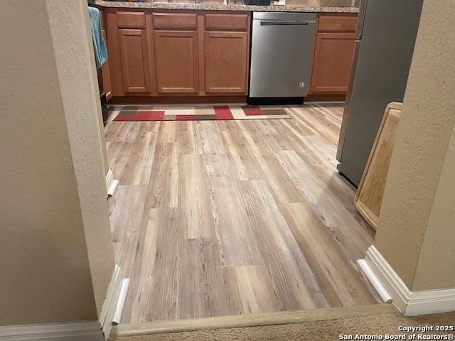 kitchen featuring light hardwood / wood-style floors, light stone counters, and stainless steel appliances