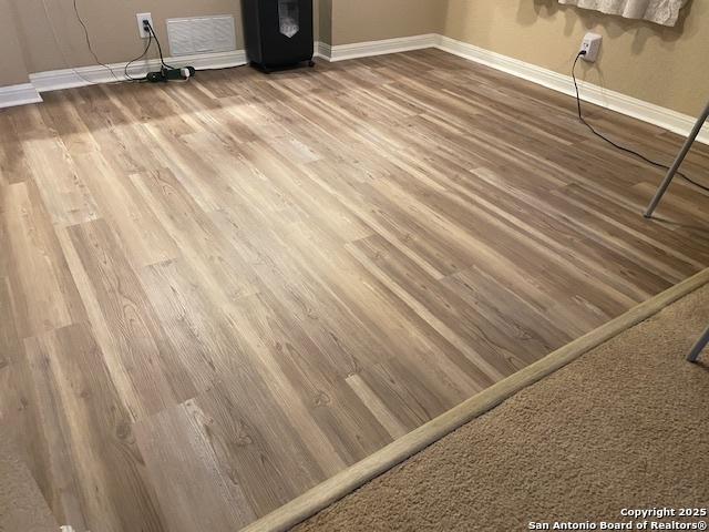 room details with hardwood / wood-style flooring and black fridge