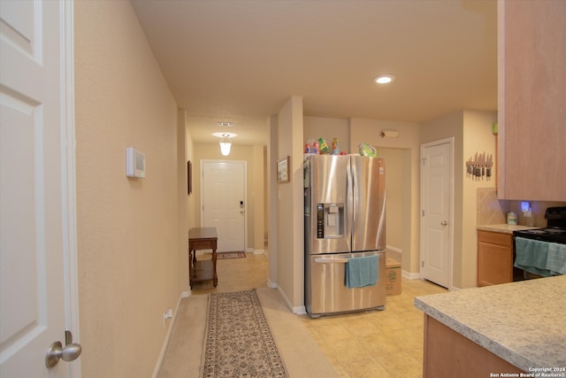 kitchen with black electric range oven and stainless steel refrigerator with ice dispenser