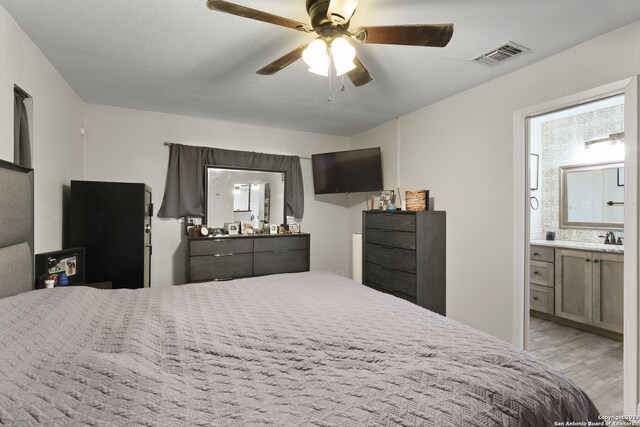 bedroom with light hardwood / wood-style floors, connected bathroom, a textured ceiling, ceiling fan, and sink