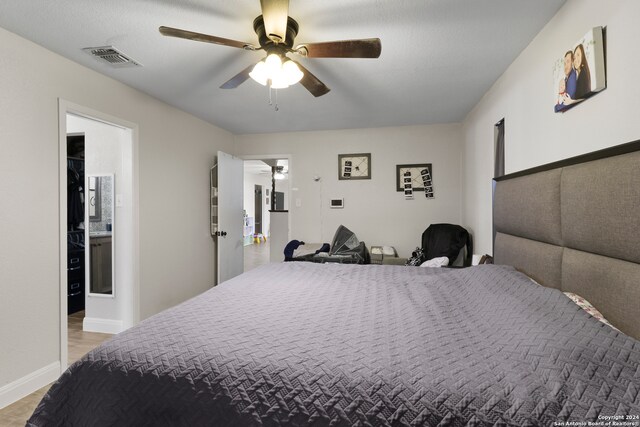 bedroom featuring light hardwood / wood-style flooring, ceiling fan, and ensuite bathroom