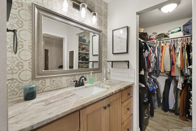 bathroom with vanity, a textured ceiling, tasteful backsplash, and hardwood / wood-style flooring