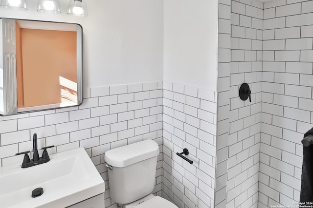 bathroom with tile walls, vanity, and toilet