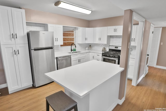 kitchen with decorative backsplash, white cabinets, stainless steel appliances, light hardwood / wood-style flooring, and sink