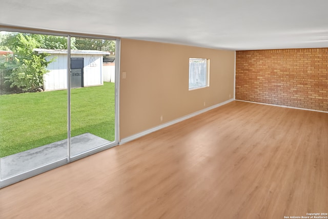 unfurnished room with brick wall and wood-type flooring