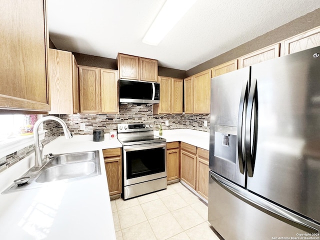 133 Rio Grande St, Uvalde, TX 78801 - kitchen featuring stainless steel appliances, a sink, light countertops, light tile patterned floors, and tasteful backsplash